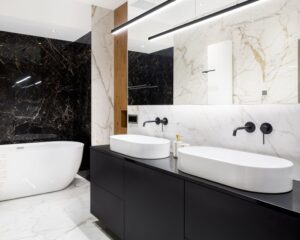 A black and white bathroom with marble walls and black cabinets and countertops.