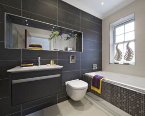 A contemporary urban bathroom design with black tile and yellow accents.
