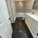 A marble floor enhances the elegance of this white and black bathroom design.