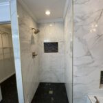 A bathroom with marble floors and a walk-in shower.