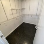 A walk-in closet with shelves and a black floor.