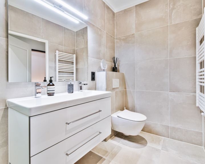 A white bathroom with a toilet and sink, featuring a modern bathroom design.