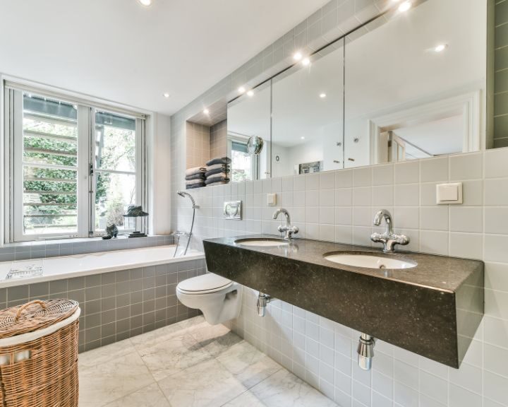 A bathroom with two sinks on the bathroom countertop and a bathtub.