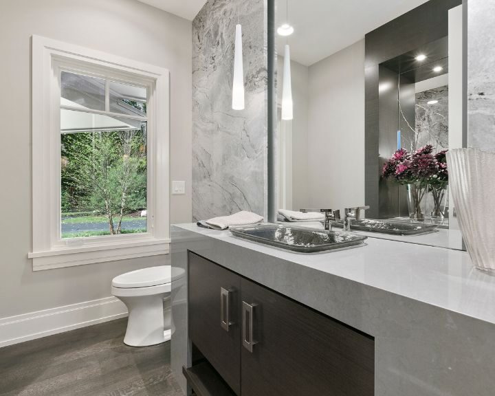 A modern bathroom with a marble counter top and window.