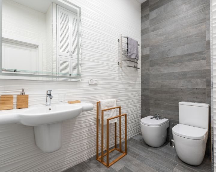 A modern bathroom design with a white toilet, sink and mirror.