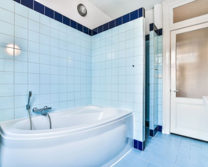 A blue tiled bathroom with a tub and sink.